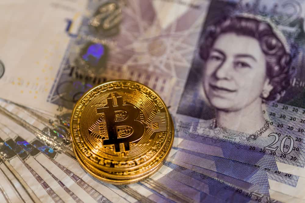 Биткойны над банкнотами британского фунта. Источник: shutterstock.com